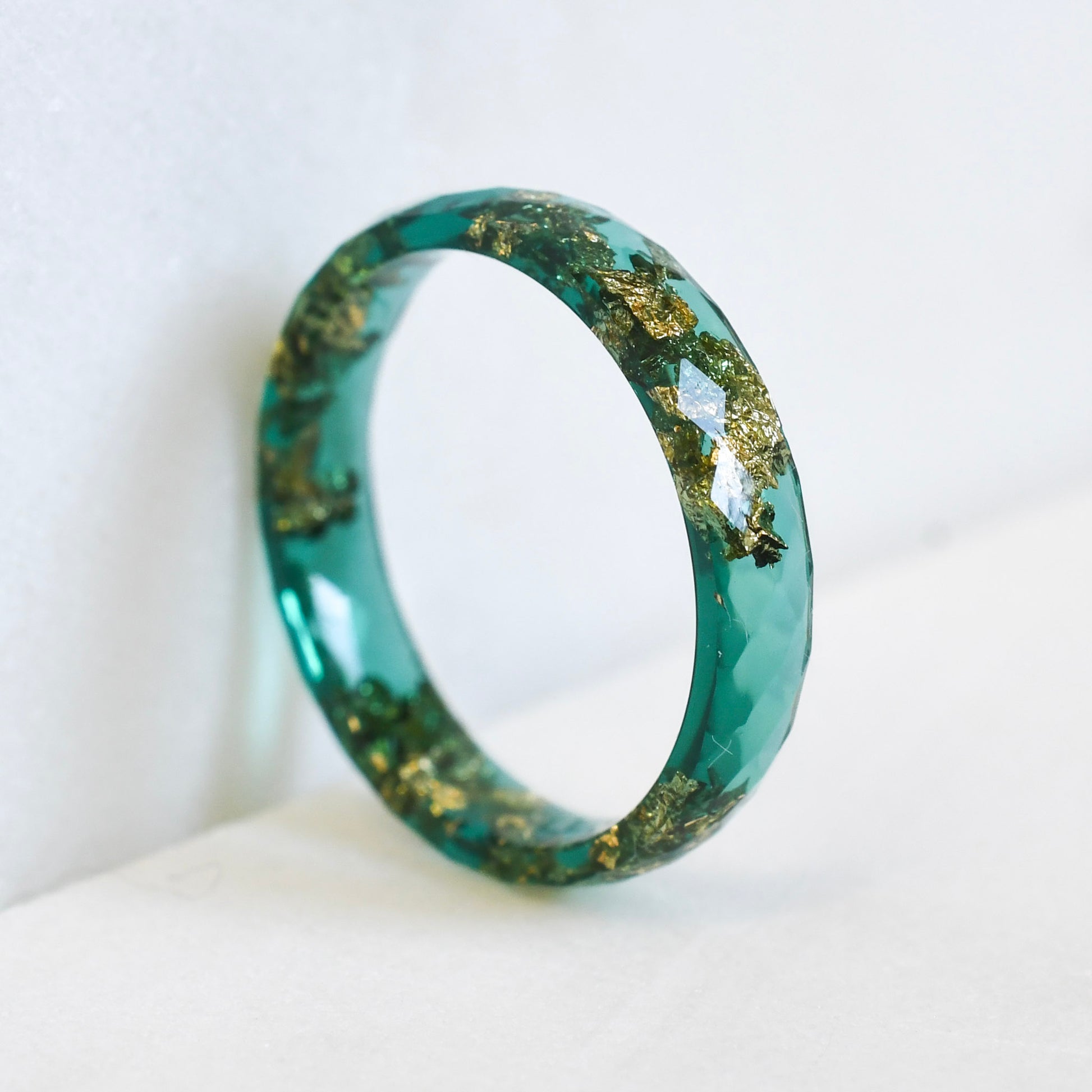 green resin ring with gold flakes on white background