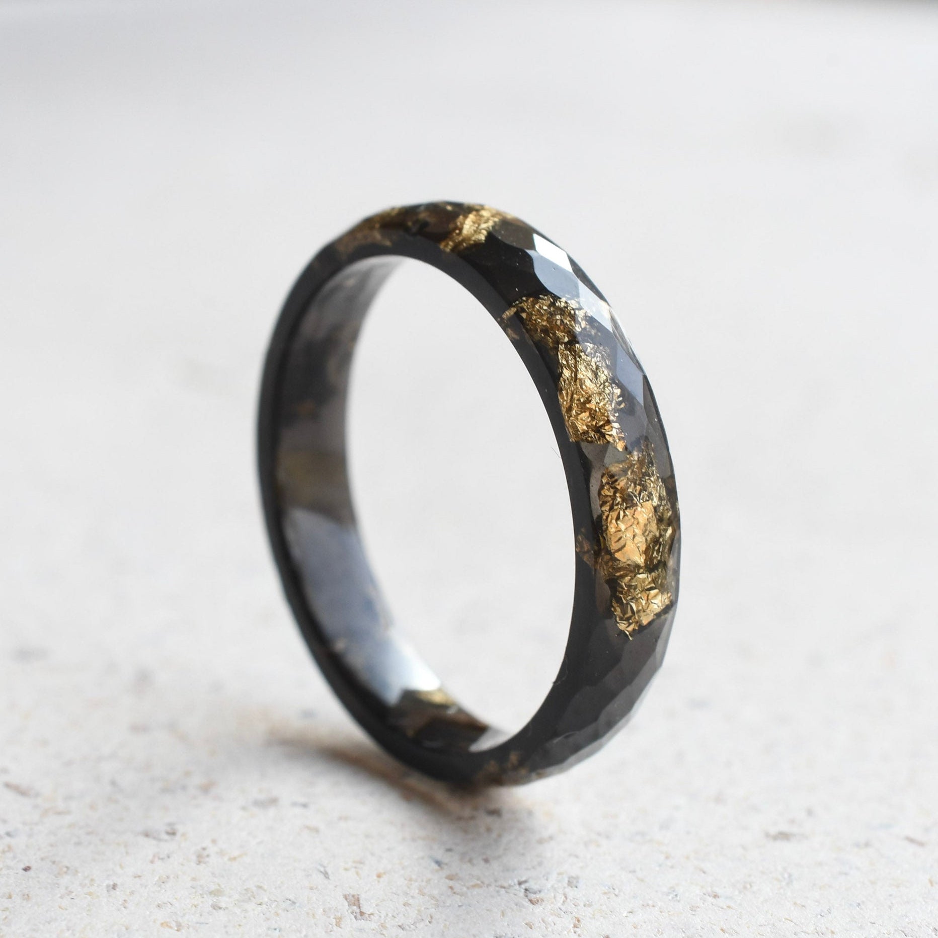 Black ring with gold inlay on a light gray surface
