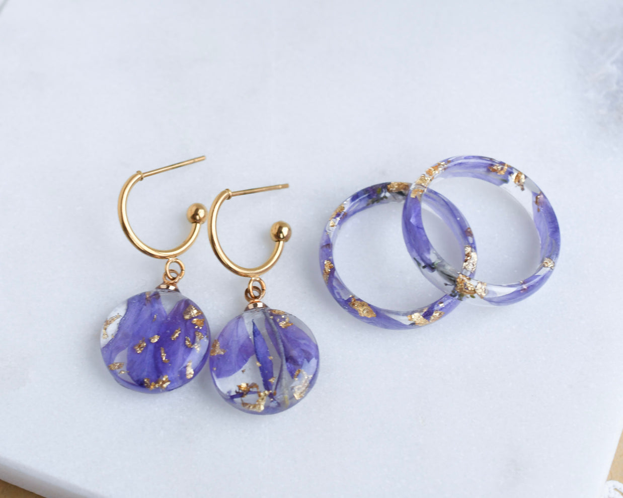 Pair of purple earrings with gold accents on a white surface