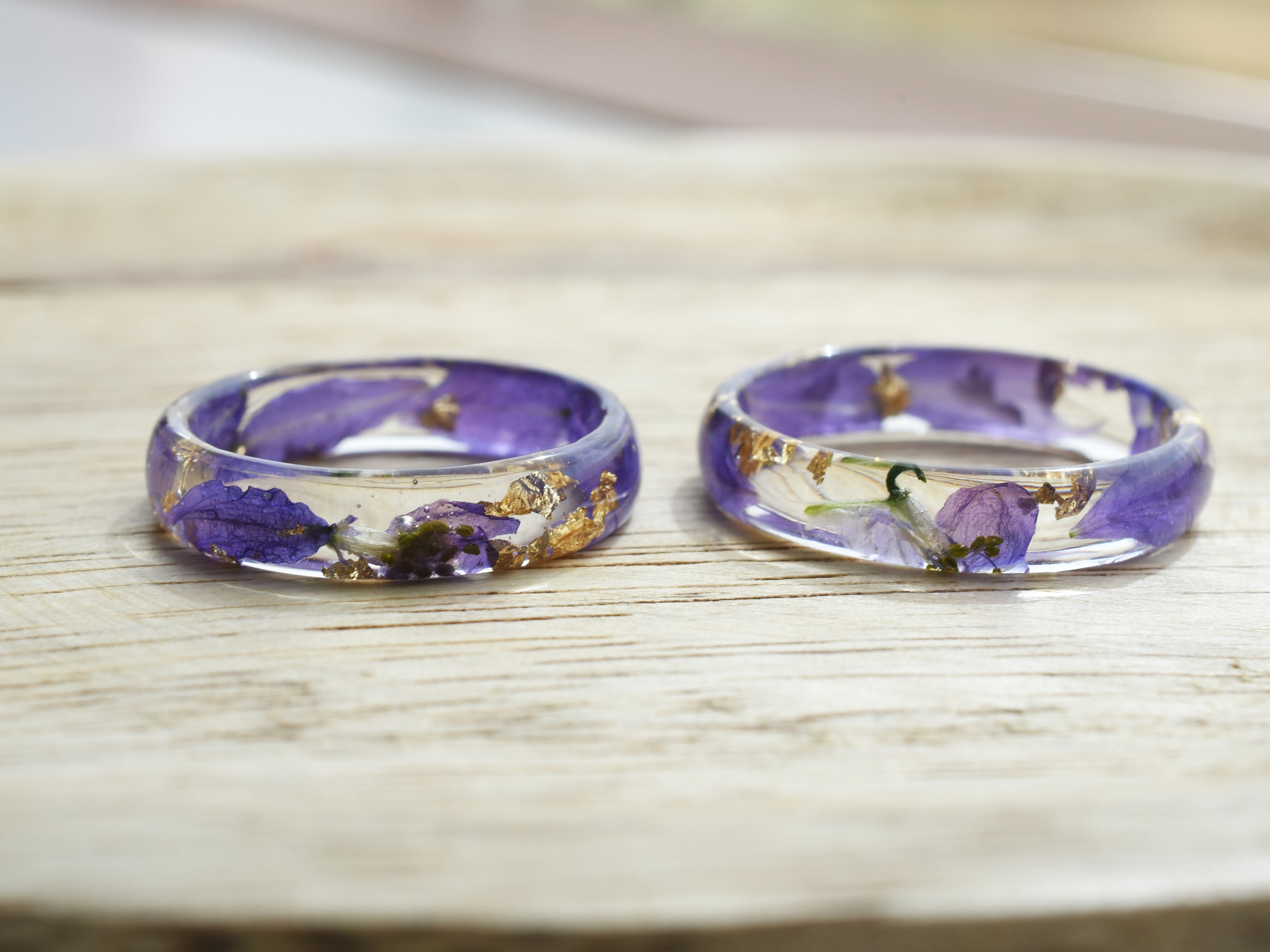 Side view of botanical resin ring showing domed surface and vibrant larkspur inside