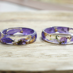 Side view of botanical resin ring showing domed surface and vibrant larkspur inside