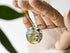 Close-up of forget-me-not flowers and mushrooms inside clear resin pendant