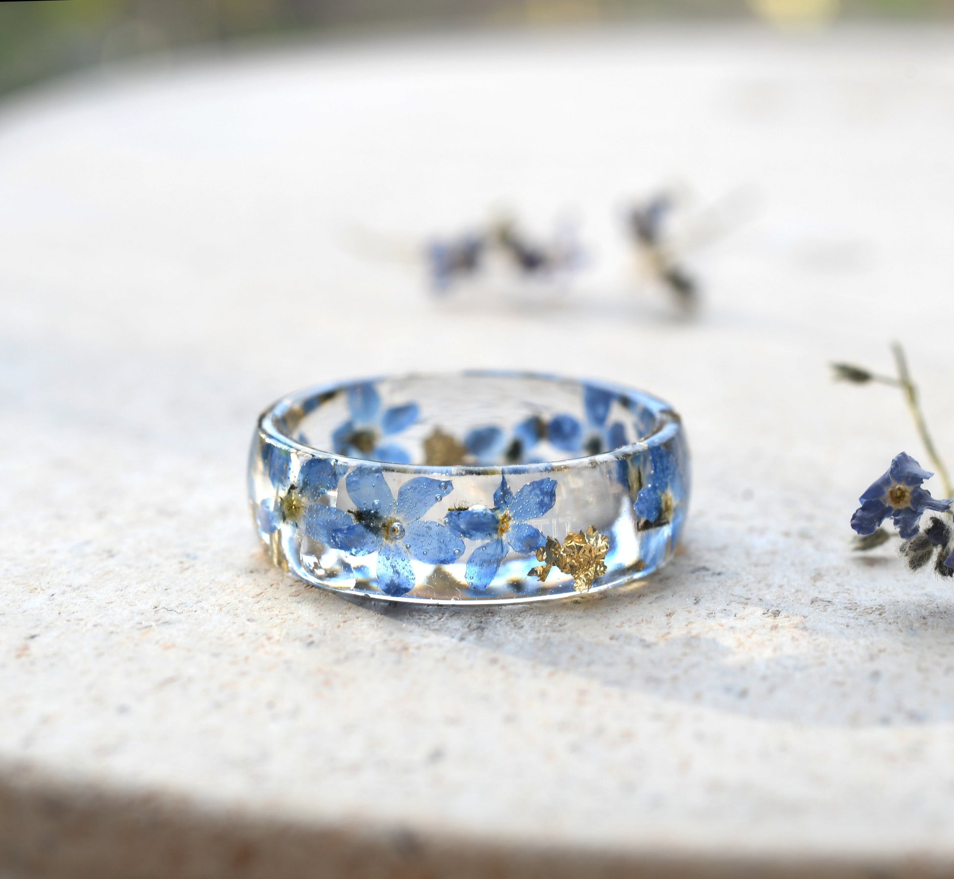 Unique floral resin ring with gold flakes and forget-me-nots on a glossy wide band