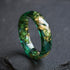 close up faceted emerald ring with metallic gold leaf