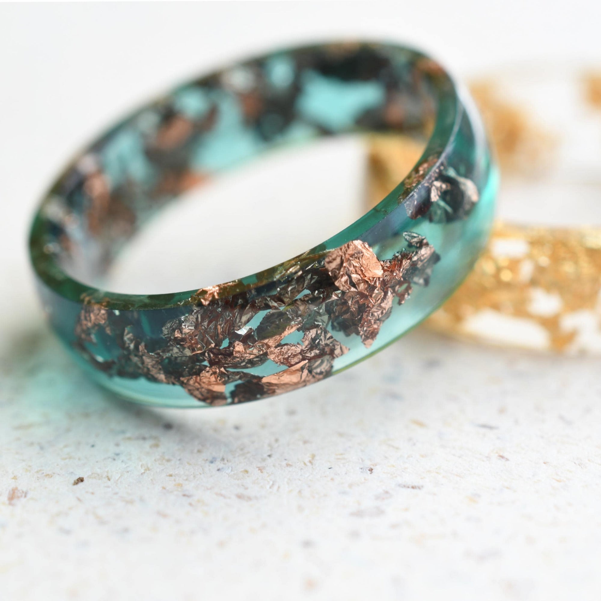 Close-up of real rose gold flakes inside emerald resin handmade ring