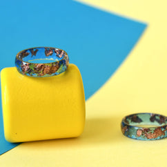 Close-up of metallic rose gold flakes in blue resin ring