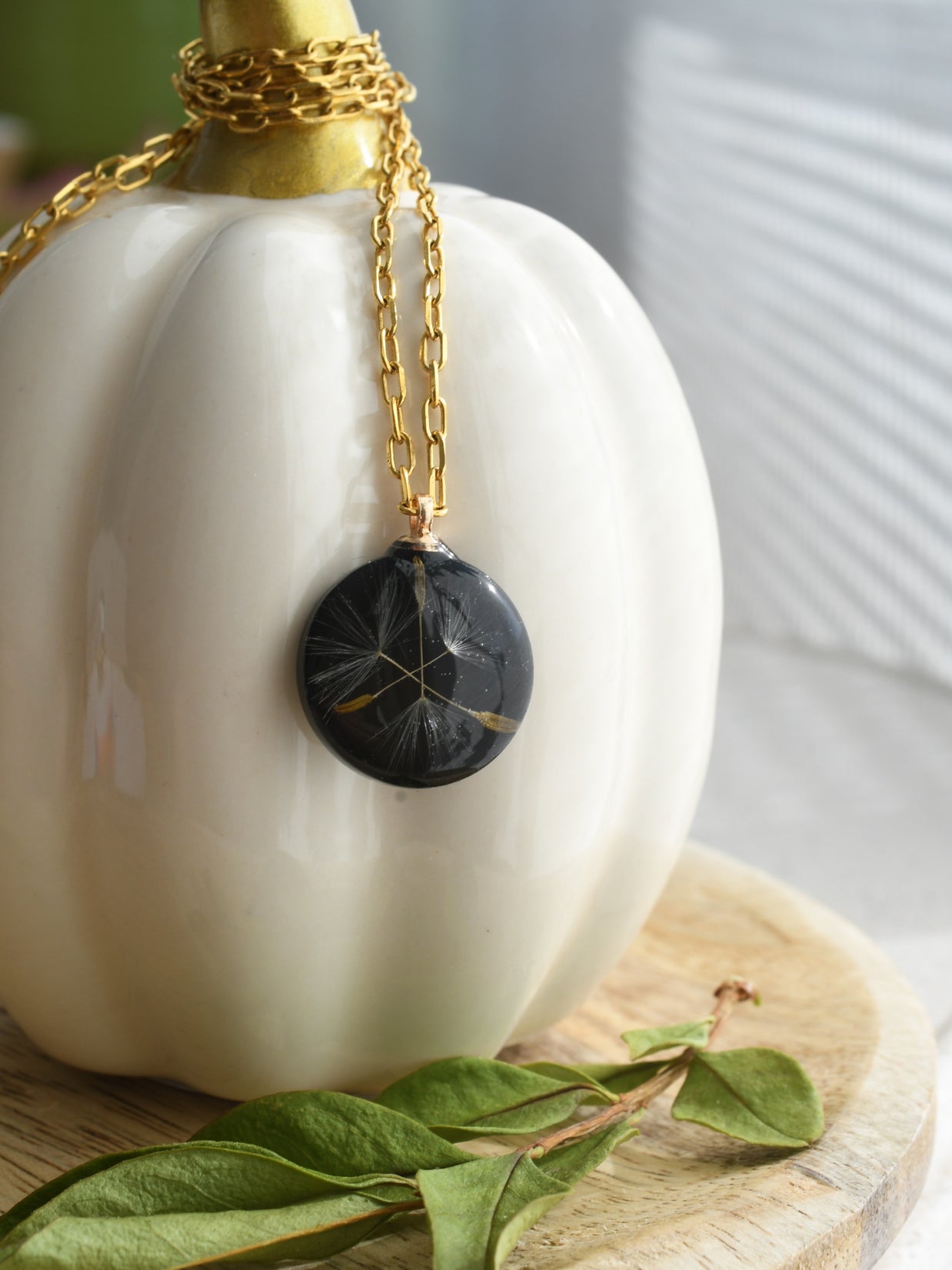Handmade dandelion seed necklace in glossy black resin with gold-plated link chain