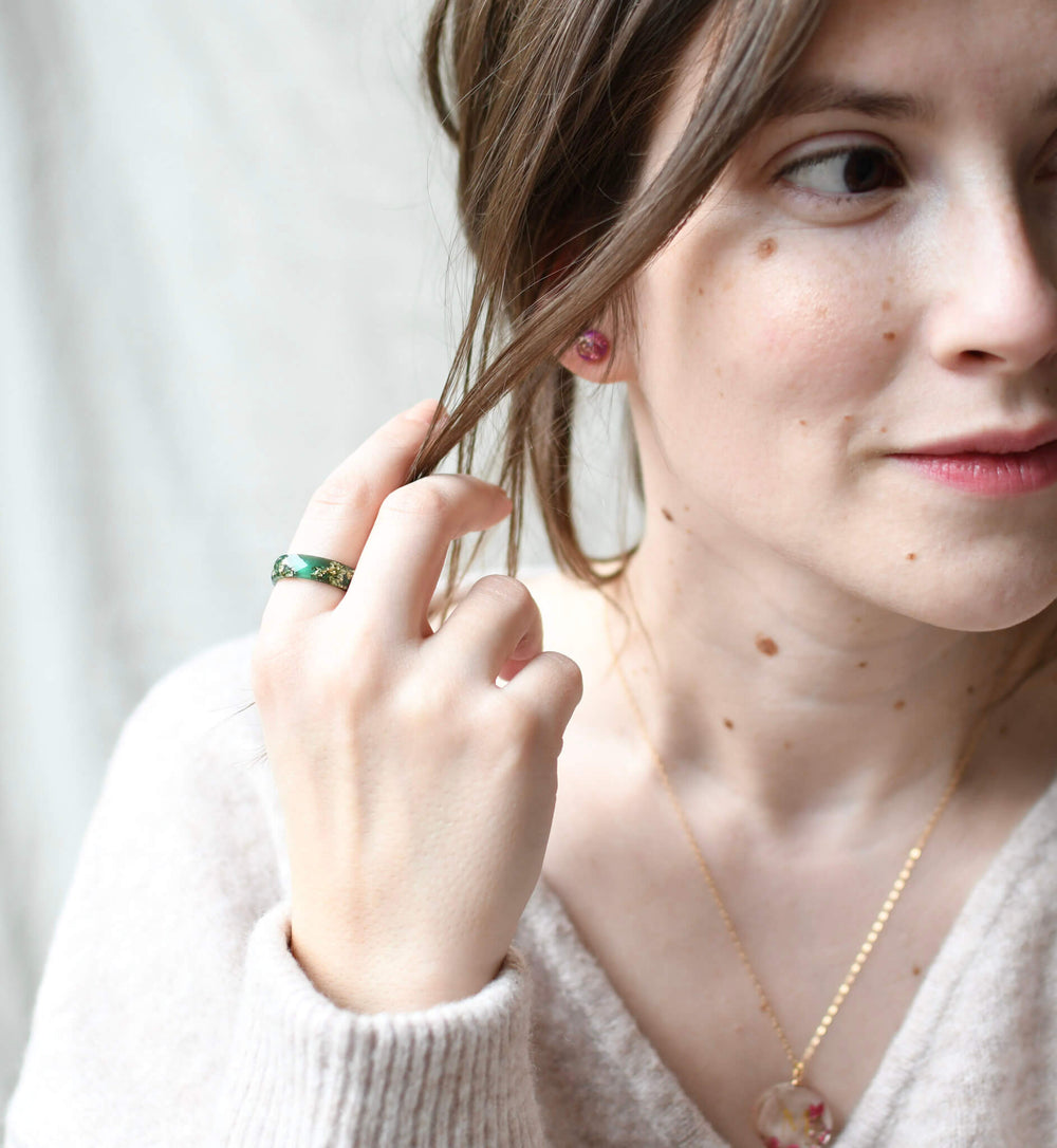 Woman wearing handmade floral resin jewelry – green ring, pink earrings, and botanical necklace by Resity, crafted in Vienna.