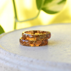 Two amber-colored rings on a white surface with a blurred green background