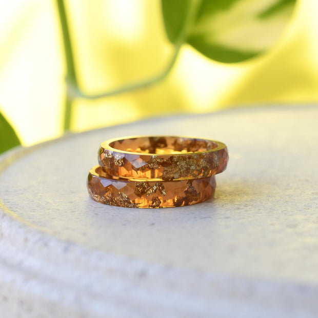 Two amber-colored rings on a white surface with a blurred green background
