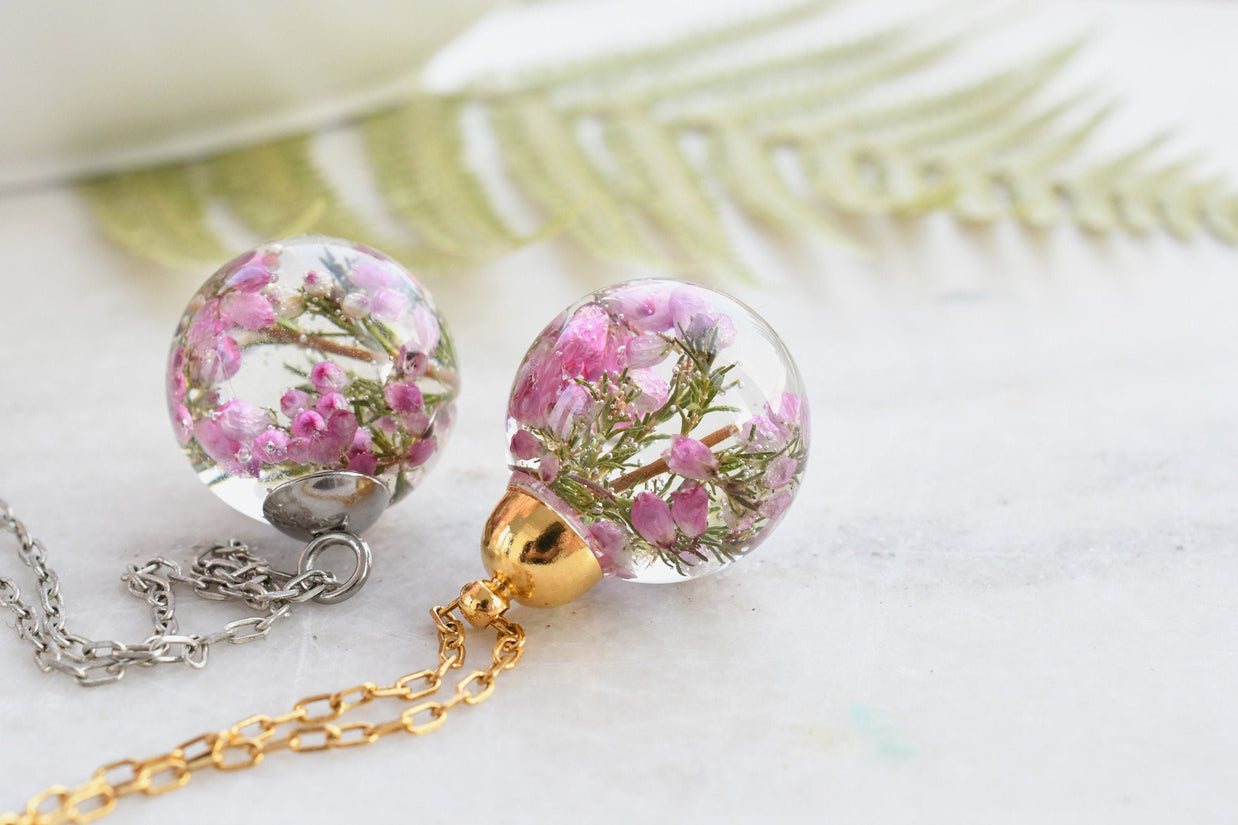 Flatlay of Heather Moon Necklace with pink heather suspended in resin sphere
