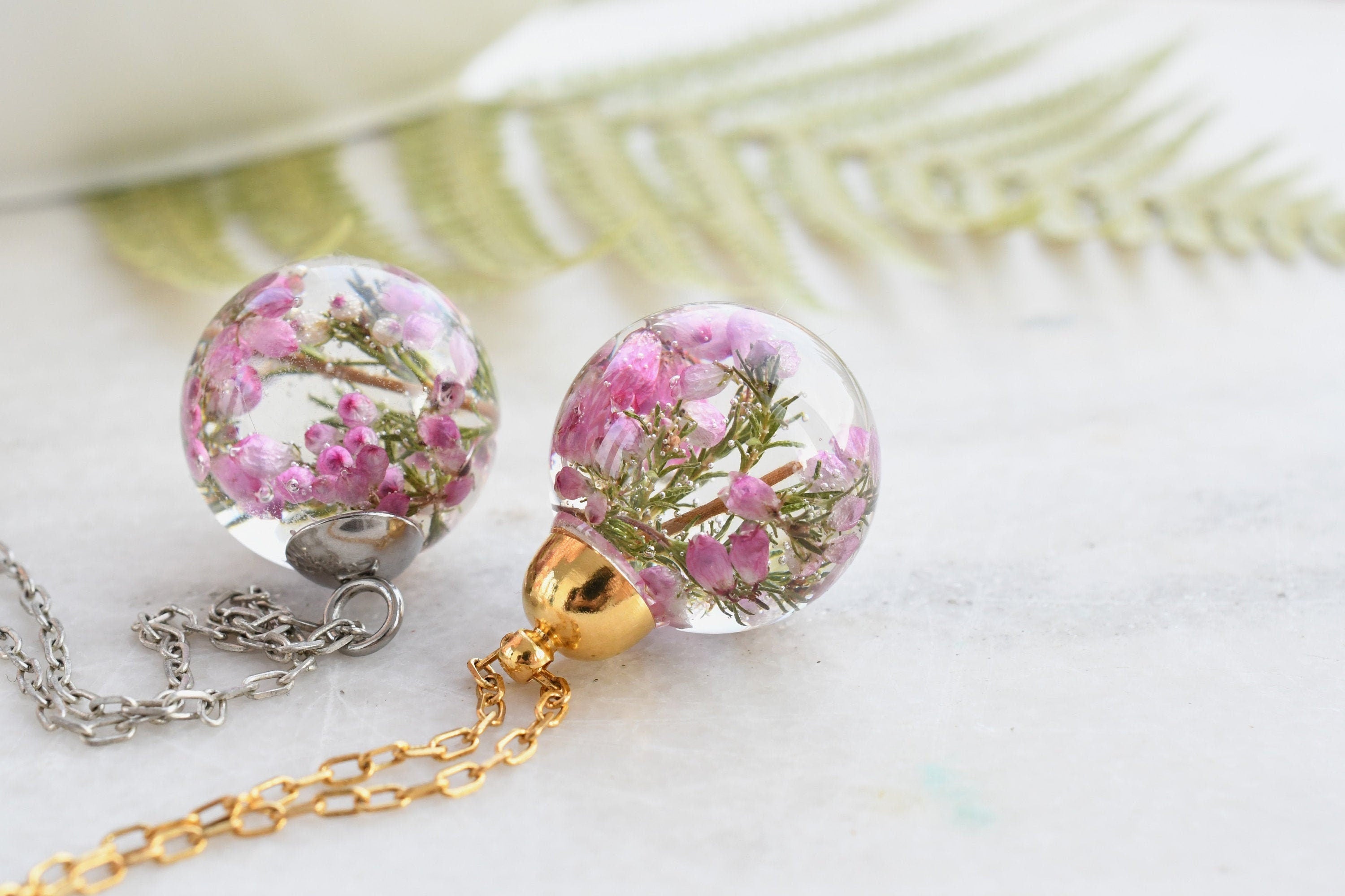 Flatlay of Heather Moon Necklace with pink heather suspended in resin sphere