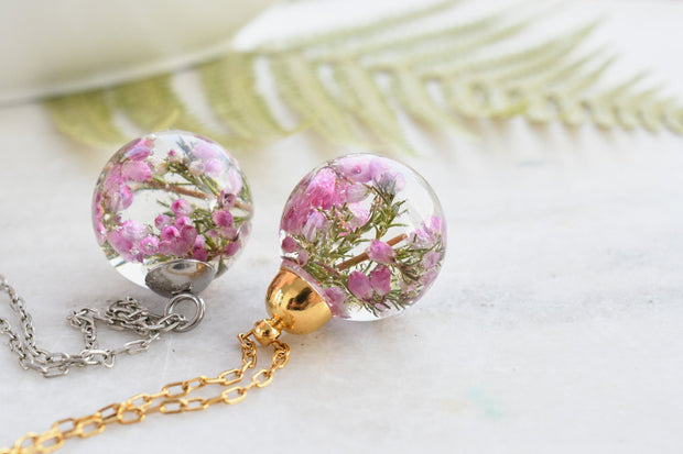 Flatlay of Heather Moon Necklace with pink heather suspended in resin sphere