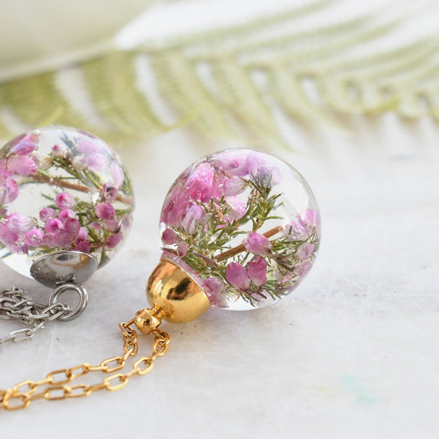 Flatlay of Heather Moon Necklace with pink heather suspended in resin sphere