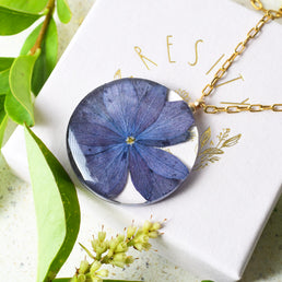 Close-up of purple hydrangea flower preserved inside clear resin pendant