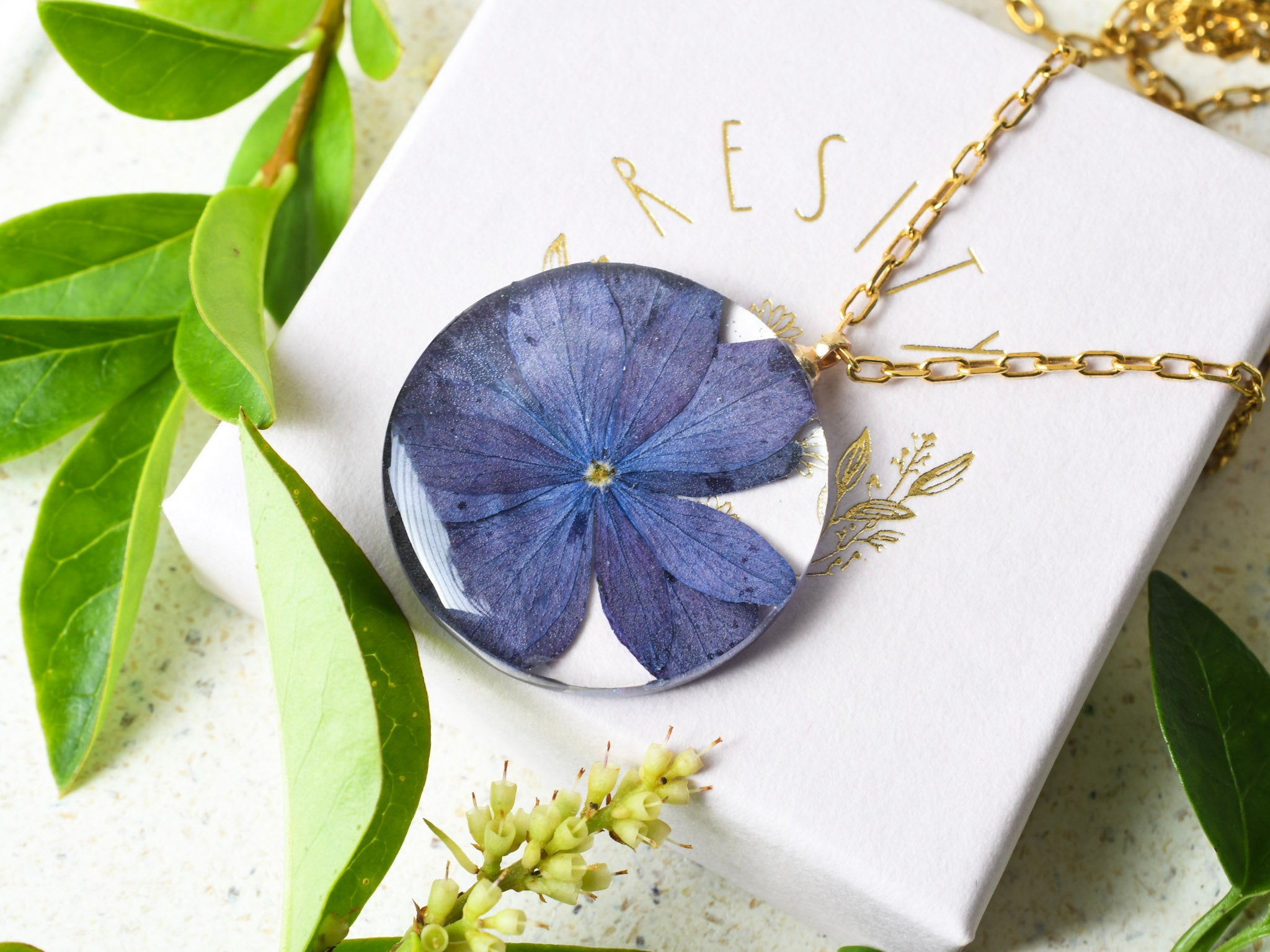 Close-up of purple hydrangea flower preserved inside clear resin pendant