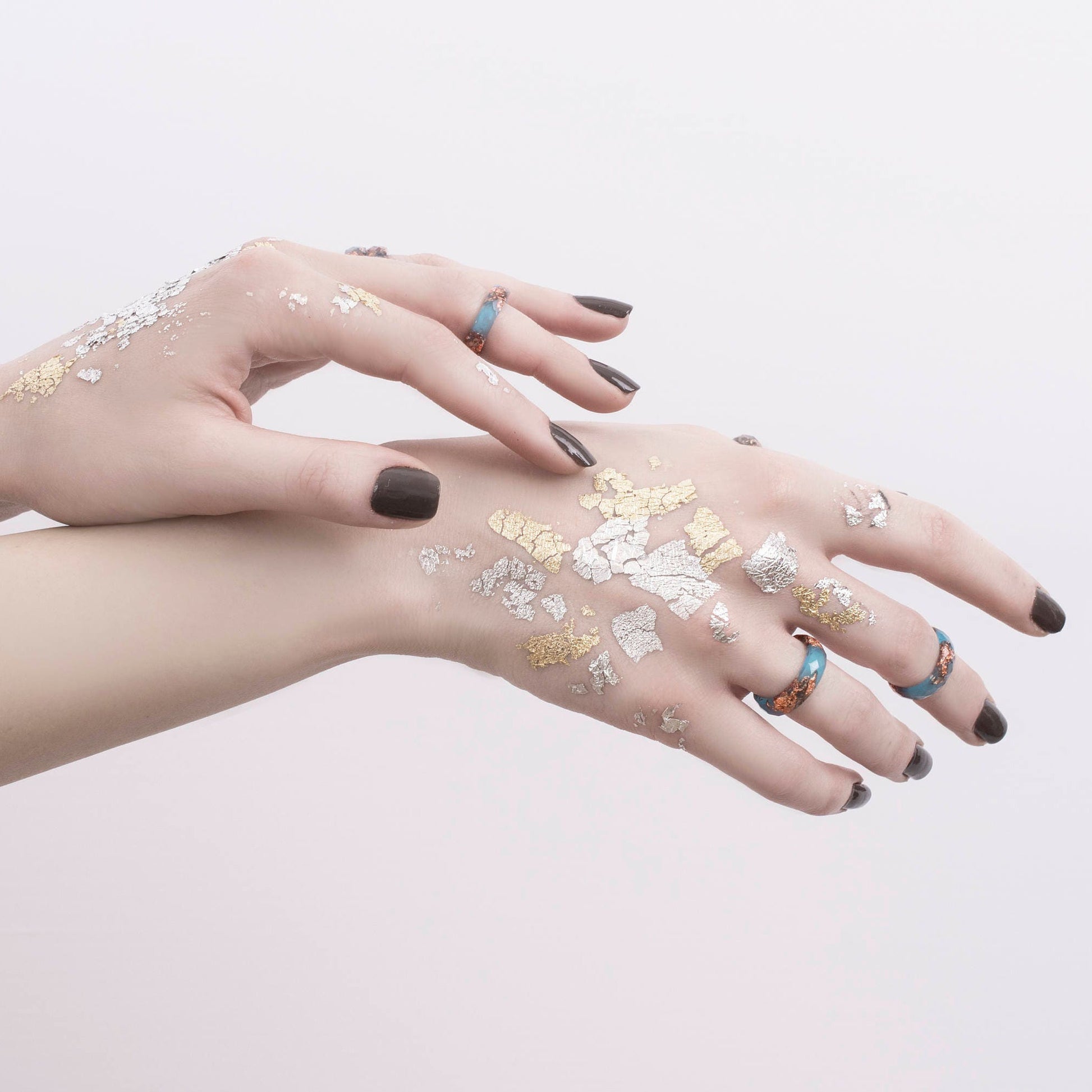 Hands with temporary tattoos on a light pink background
