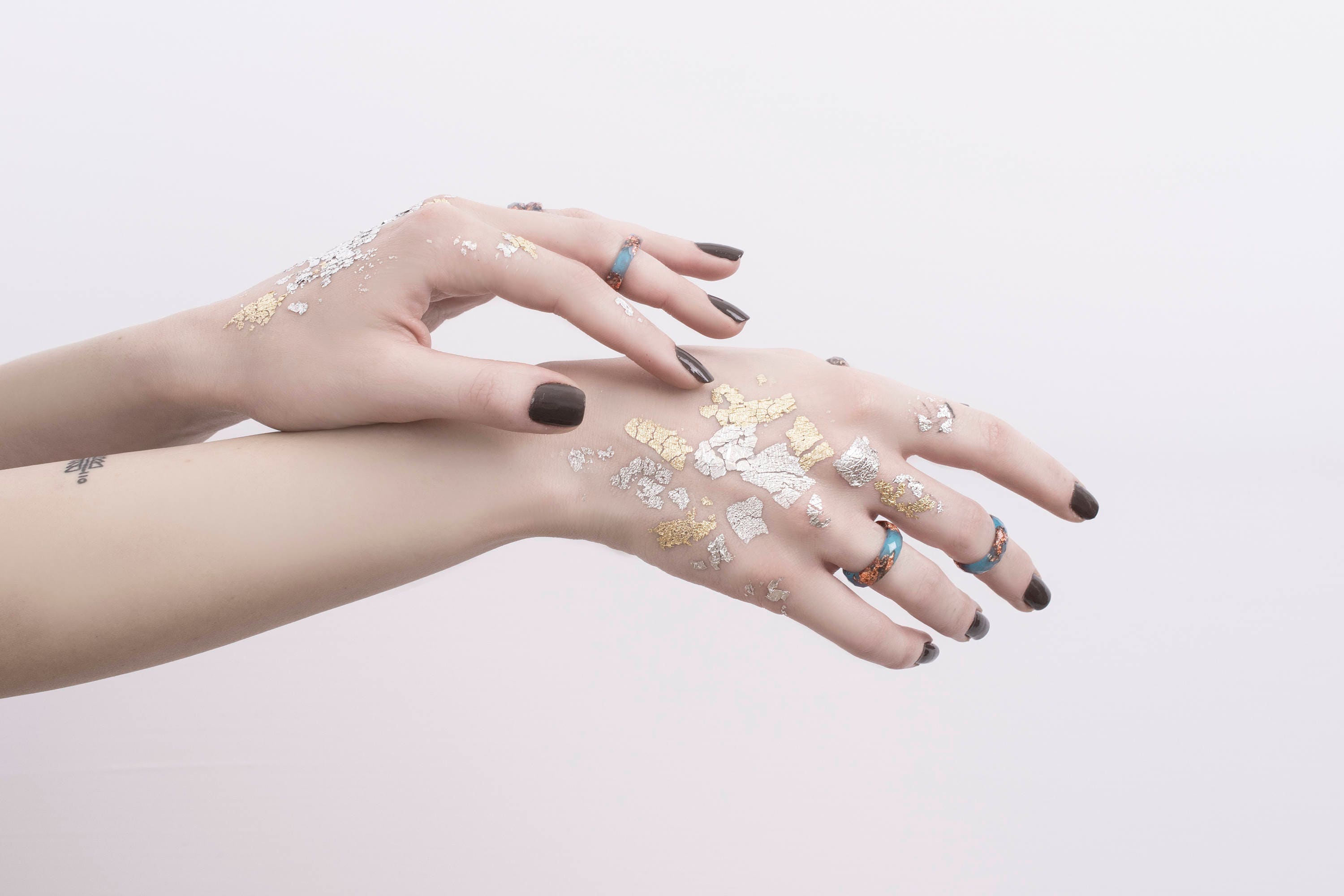 Hands with temporary tattoos on a light pink background