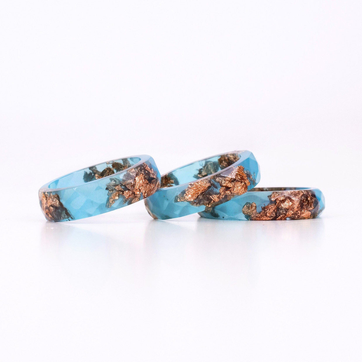 Three turquoise rings with copper inclusions on a white background