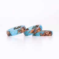 Three turquoise rings with copper inclusions on a white background