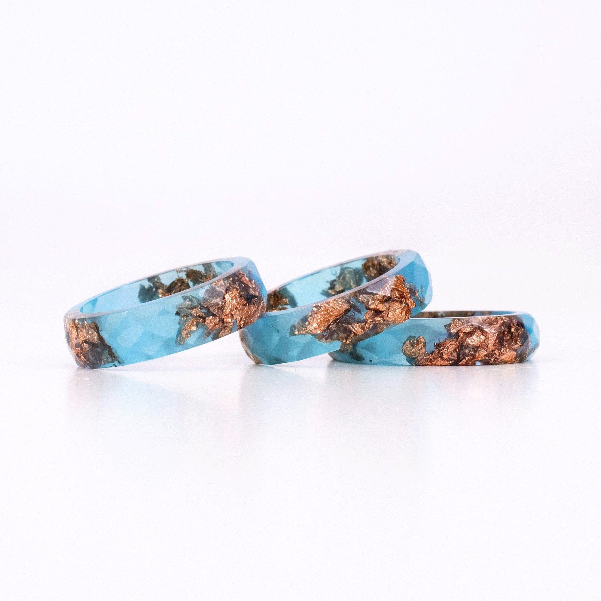 Three turquoise rings with copper inclusions on a white background