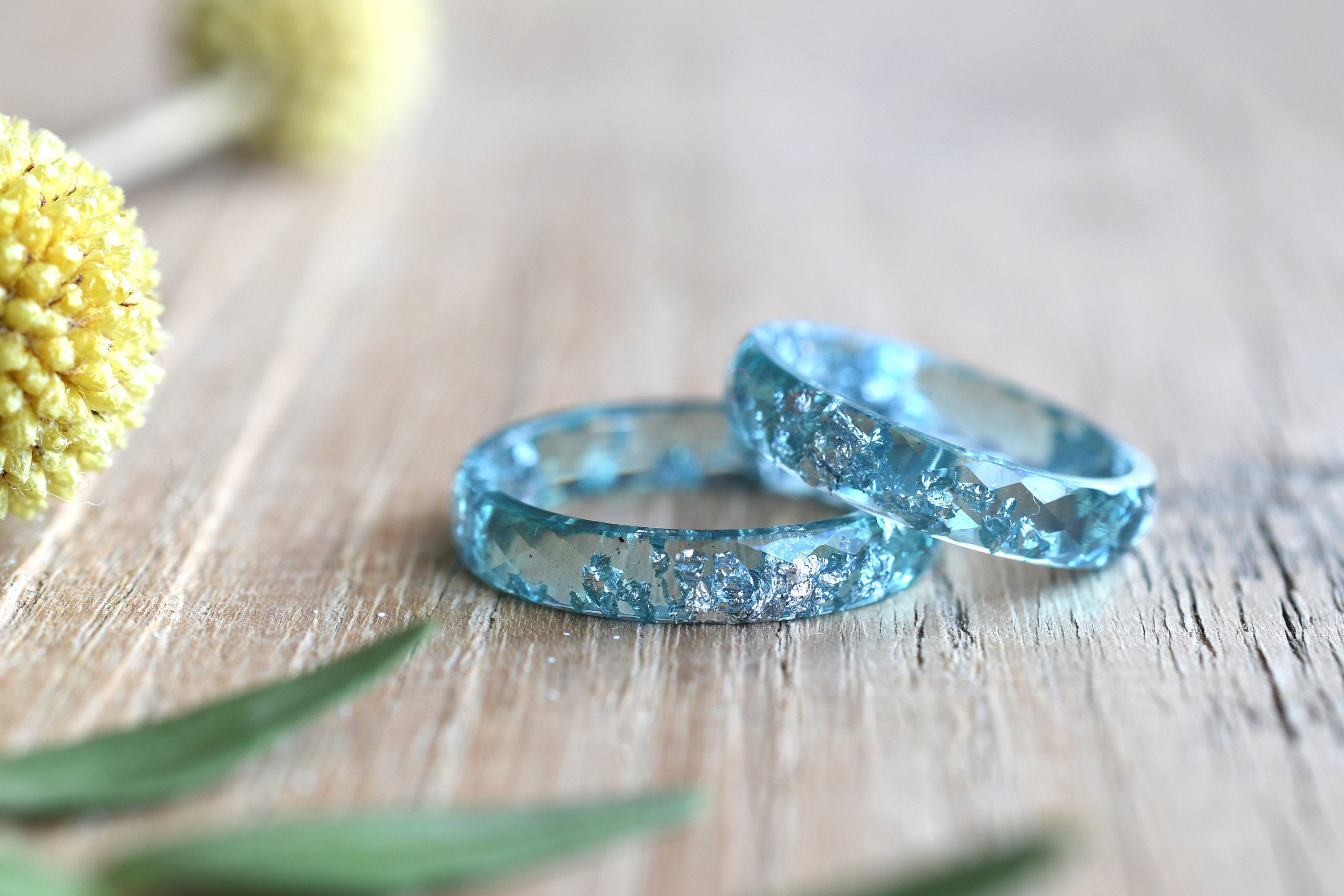 Two turquoise resin rings with silver glitter embedded inside. The rings are stacked on top of each other.