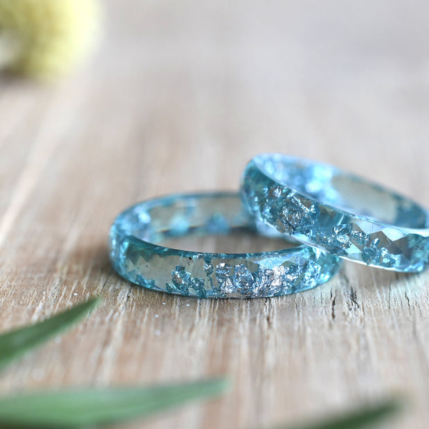Two turquoise resin rings with silver glitter embedded inside. The rings are stacked on top of each other.