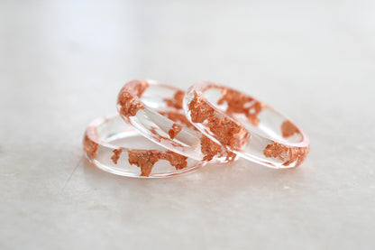 Two rose gold and clear resin rings on a light gray background