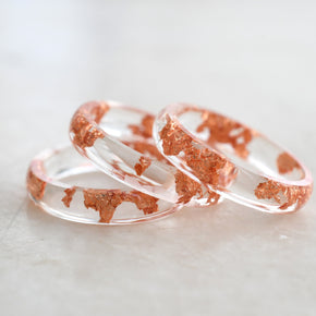 Two rose gold and clear resin rings on a light gray background
