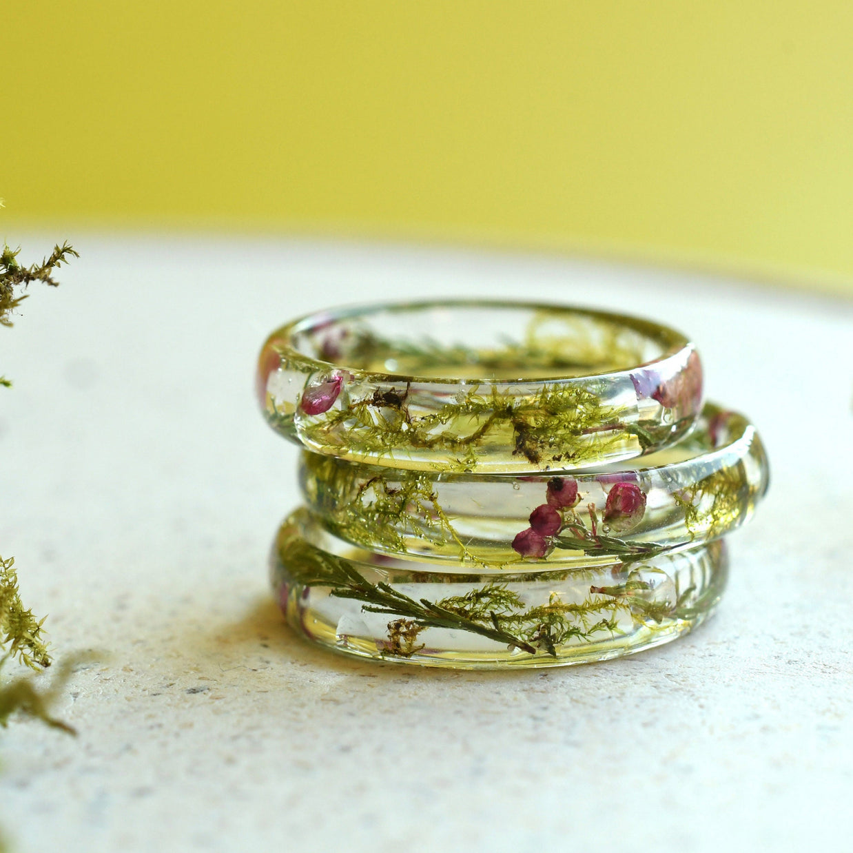 Close-up of &#39;Enchanted Whisper Resin Ring&#39; showcasing its smooth surface and dried moss accents