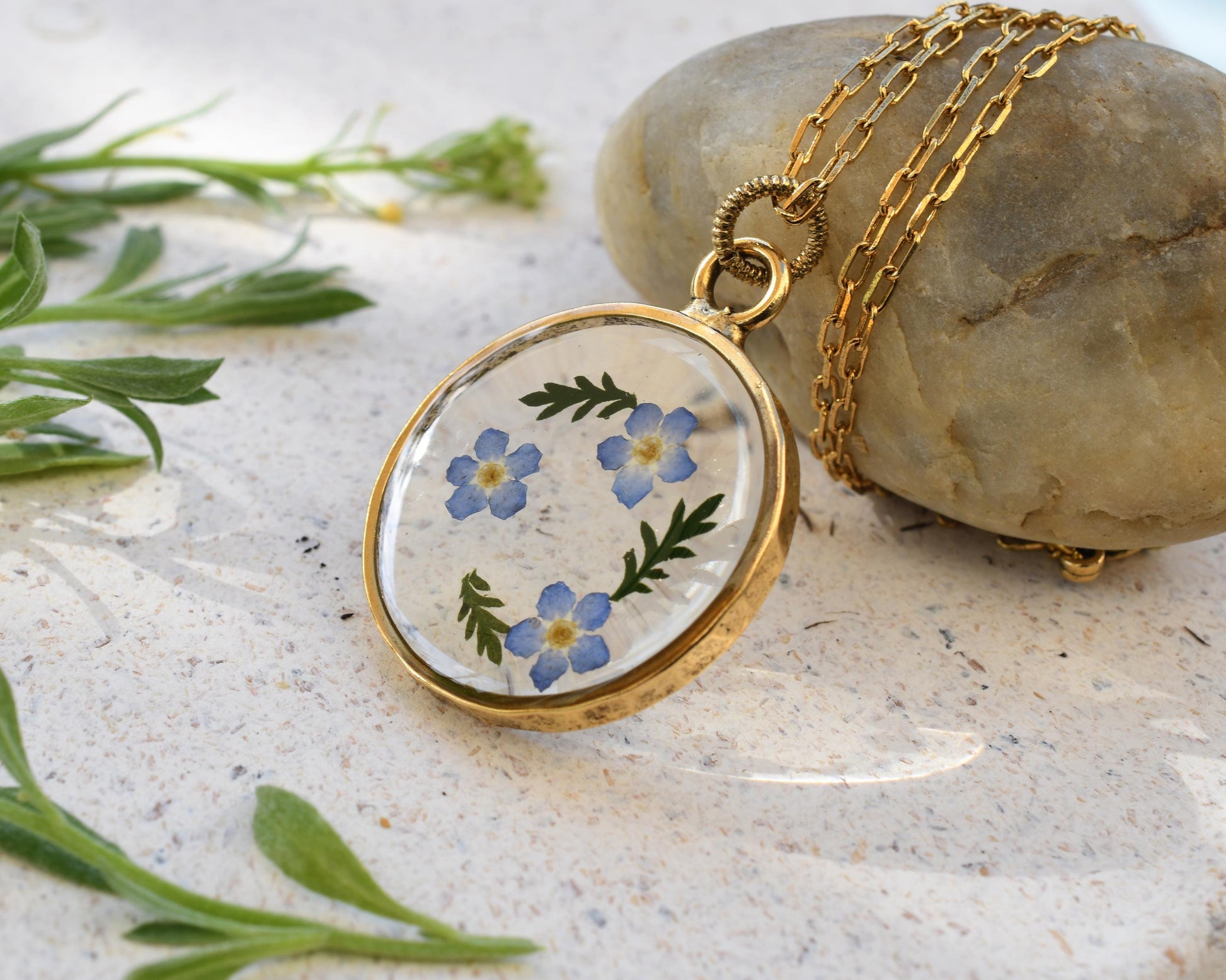 Nature-inspired resin pendant with dried forget-me-not flowers, ready for gift giving, for a sentimental present idea.