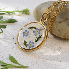 Nature-inspired resin pendant with dried forget-me-not flowers, ready for gift giving, for a sentimental present idea.