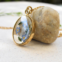 Side view of a forget-me-not resin pendant on a gold chain, emphasizing its lightweight and elegant craftsmanship.