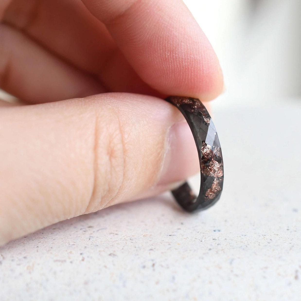 Thin black resin ring with faceted design and customizable rose gold leaf detail.