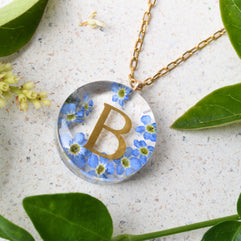 Handmade floral necklace with custom golden letter inside resin