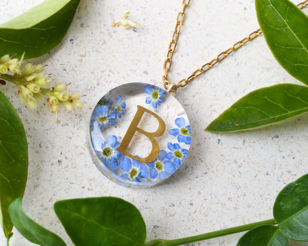 Handmade floral necklace with custom golden letter inside resin