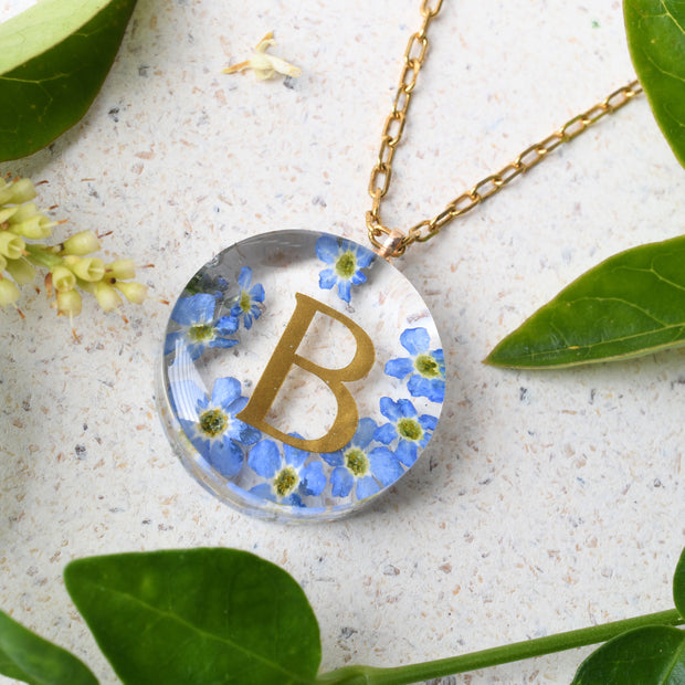 Handmade floral necklace with custom golden letter inside resin