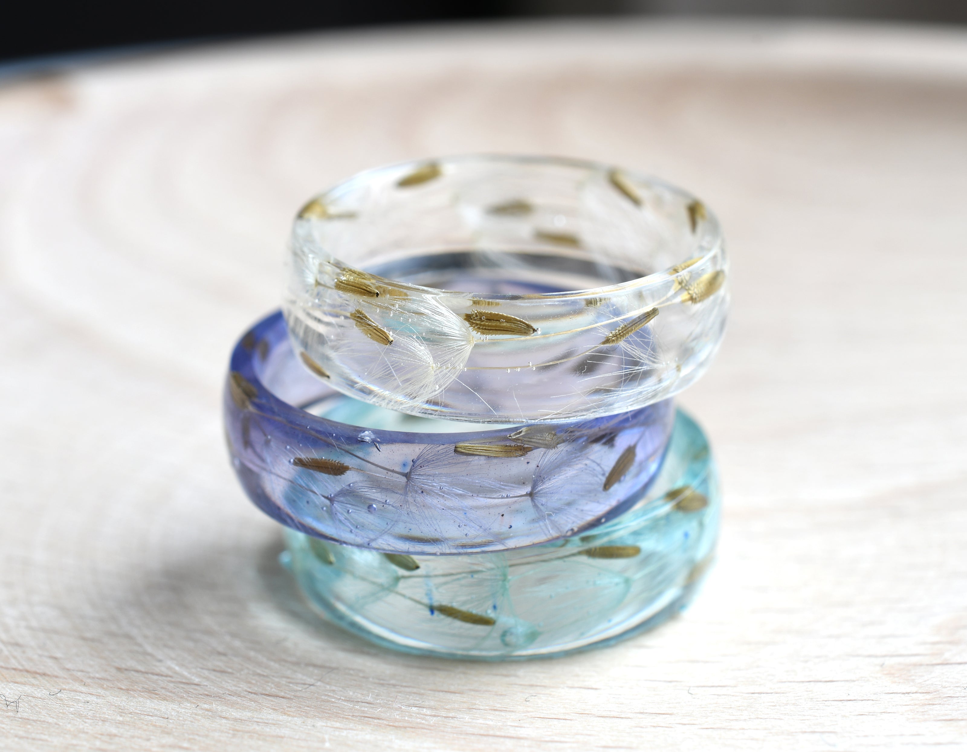 Flatlay of lavender resin wish ring with flower seed detail