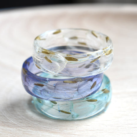 Flatlay of lavender resin wish ring with flower seed detail