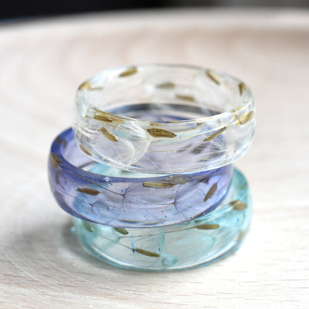 Flatlay of lavender resin wish ring with flower seed detail
