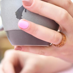 Hand holding a gray mug with a blurred background