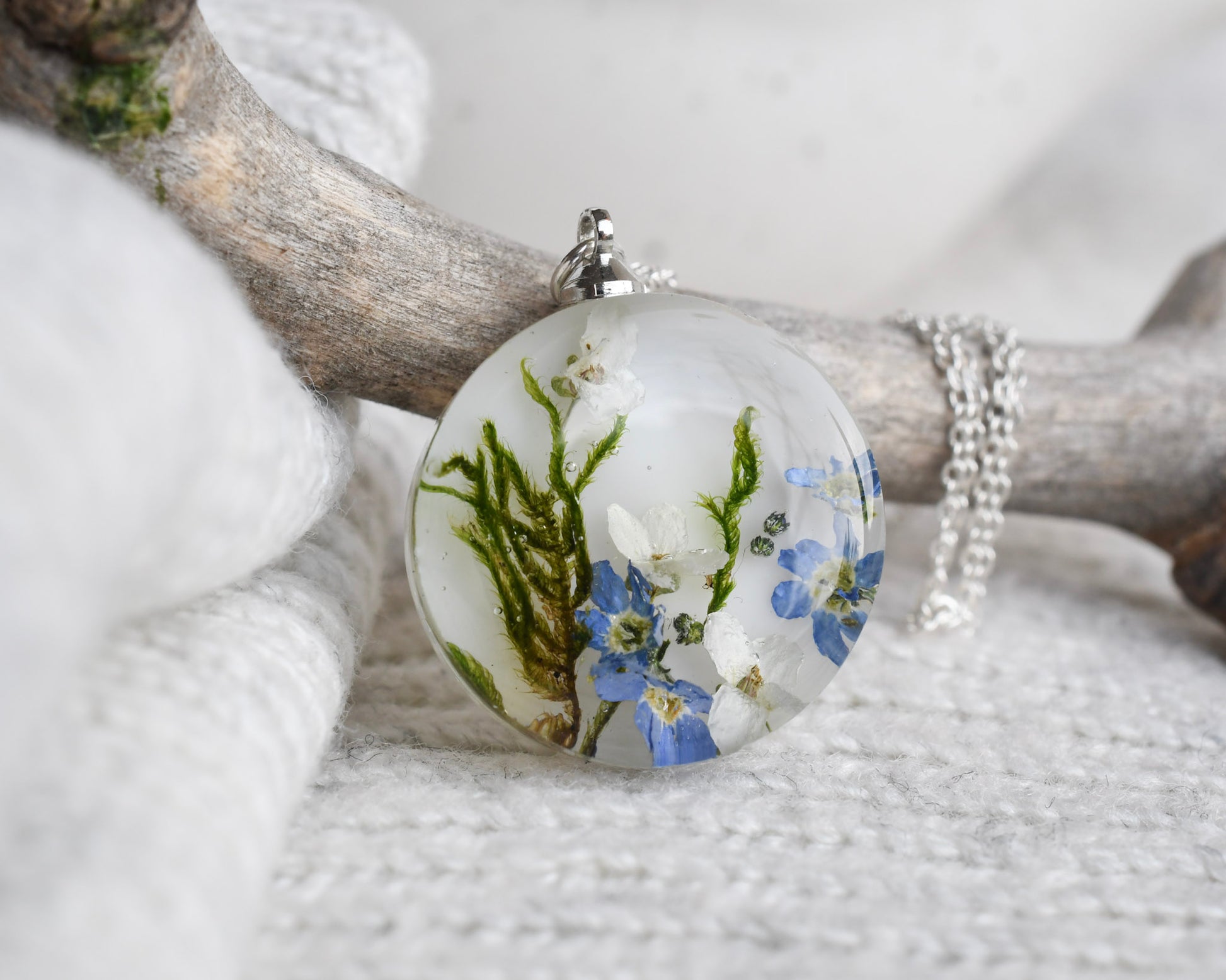 Round pendant with floral design on a branch and stones