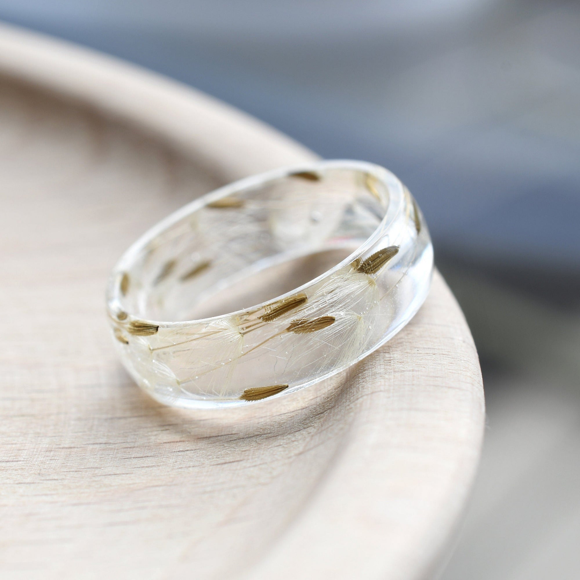 Close-up of resin ring with real dandelion seeds and smooth clear surface