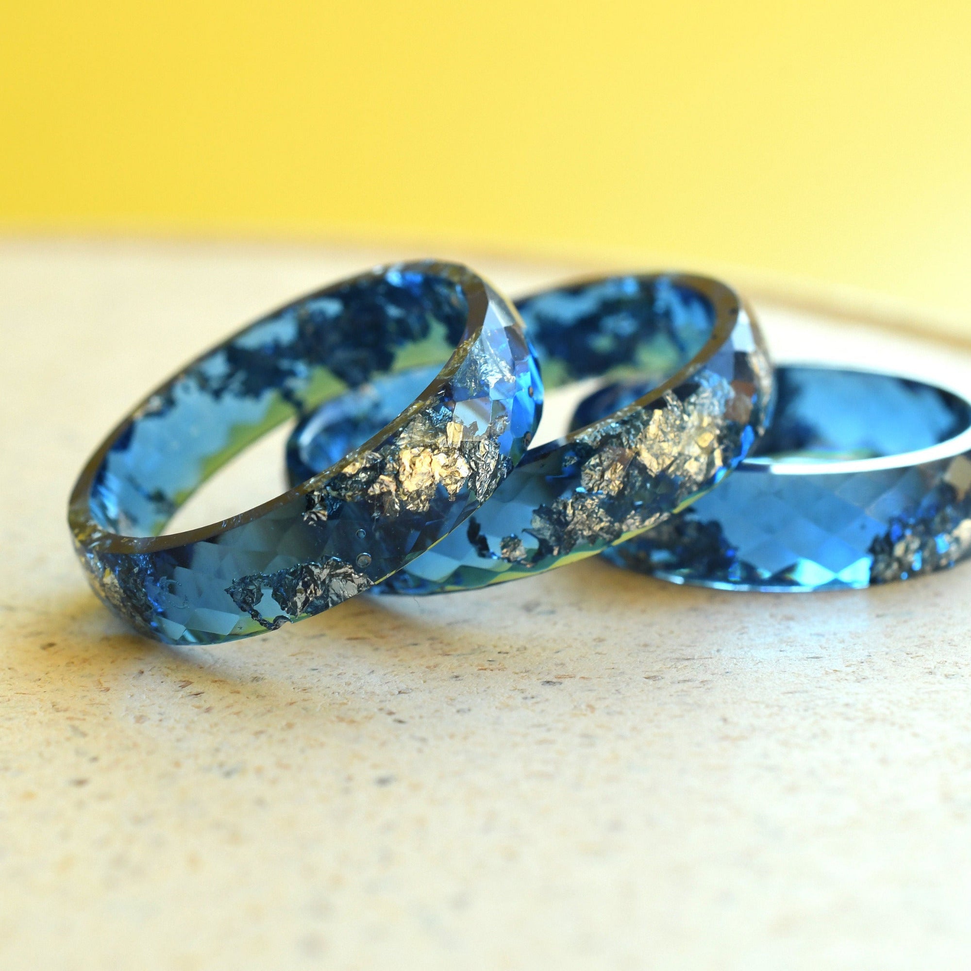 Close-up of navy blue resin ring with silver flakes and faceted surface
