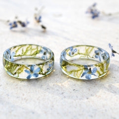 Two transparent rings with embedded flowers on a light surface.