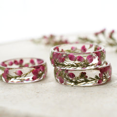 Clear resin rings with pink flowers on a white surface