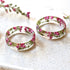 Three floral resin rings on a textured surface with pink flowers in the background.