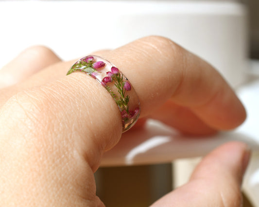 Hand model wearing pink heather resin ring, showcasing natural floral detail
