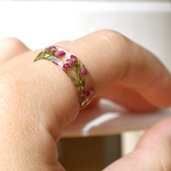 Hand model wearing pink heather resin ring, showcasing natural floral detail