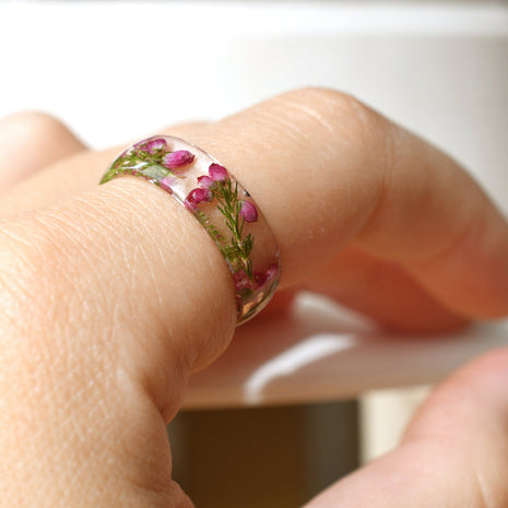 Hand model wearing pink heather resin ring, showcasing natural floral detail
